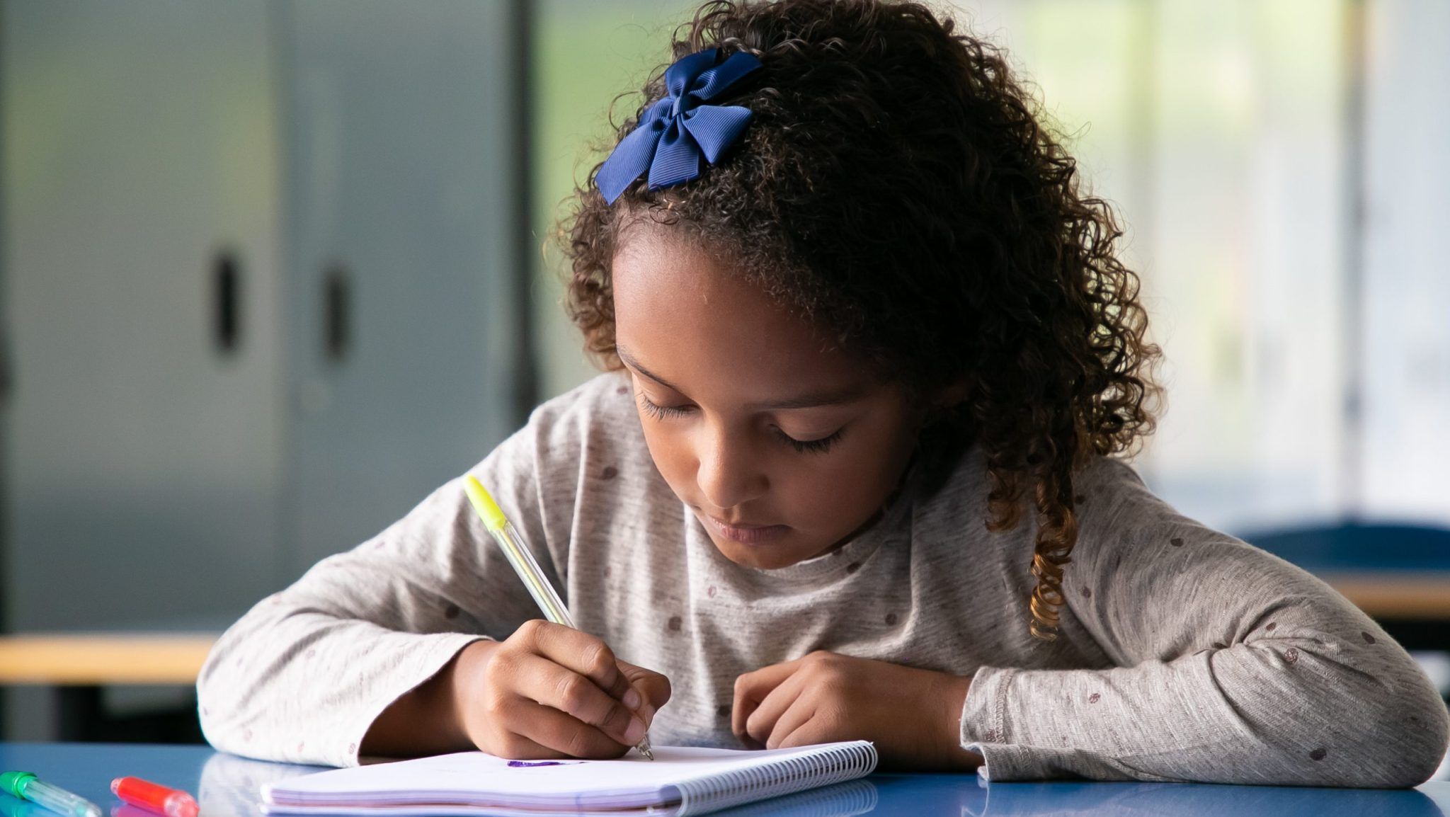 focused-mix-raced-girl-sitting-at-school-desk-and-drawing-in-copybook-scaled-e1732201996201-2048x1154.jpg